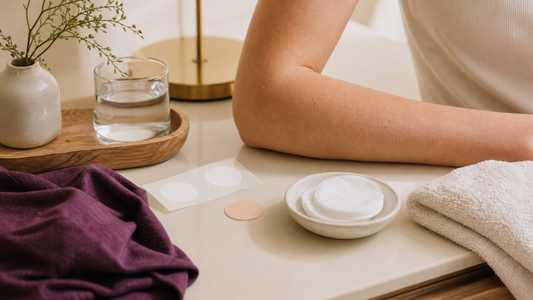 Unbranded adhesive backing, round disc, cotton pad, ceramic dish, folded towel, and an adult forearm.